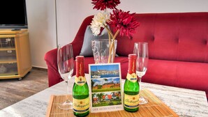 A table with two bottles of Rottkappfen beer, two wine glasses, a vase with red and white flowers, and a postcard of a scenic view. - Apartment in Klutz Near Baltic Sea Beach (Klütz)