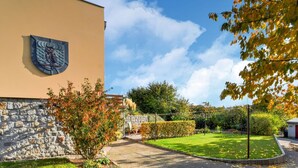 A building with a stone wall and a wooden bench. There is a well-maintained lawn and a paved walkway. - Apartment in Klutz Near Baltic Sea Beach (Klütz)