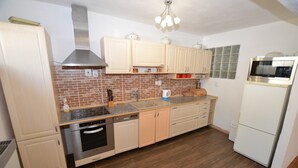 A kitchen with wooden cabinets, a stainless steel range hood, a dishwasher, a microwave, and a refrigerator. - Relaxation Holiday Home (Jiretin pod Jedlovou)