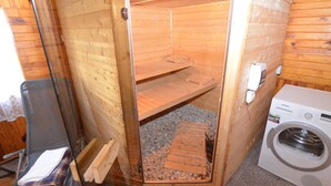 A sauna with a wooden interior, a bench, and a washing machine. - Relaxation Holiday Home (Jiretin pod Jedlovou)