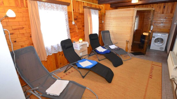A room with four reclining chairs, a washing machine, and a small table with a lamp. - Relaxation Holiday Home (Jiretin pod Jedlovou)