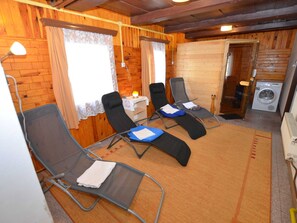 Una habitación con cuatro sillones reclinables, una lavadora y una mesita con una lámpara.