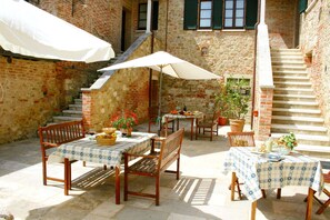 An outdoor patio with tables and chairs, a staircase, and potted plants.