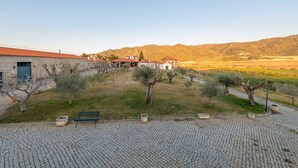 A cobblestone courtyard with a bench, a tree, and a building with a red roof. - Holiday Home on Estate With Vineyards, Olive Groves and Swimming Pool (Vila Flor)