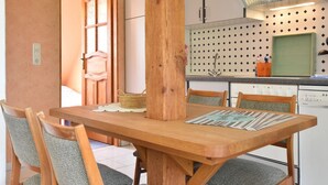 Ein Essbereich mit Holztisch und Stühlen, eine Küche mit einem gemusterten Rücksprung und eine Tür zu einem anderen Raum.