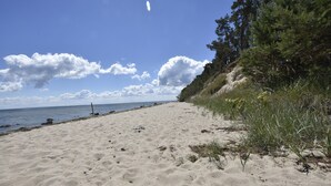 Ein sandiger Strand mit blauem Himmel und vereinzelten Wolken.