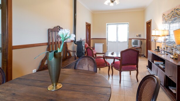 A dining area with a wooden table, red upholstered chairs, a vase with flowers, and a chandelier. - Vila Flor Pool Retreat (Vila Flor)
