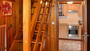 A wooden staircase leading to a kitchen with wooden cabinets and a stainless steel oven. - Relaxing Forest Escape With BBQ (Krasna Lipa)