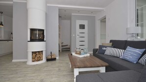 A modern living room with a fireplace, a sofa, a coffee table, and a staircase leading to another level. - A Luxury Villa in a Seaside Village.living Room, 2 Bedrooms, 2 Bathrooms, Garden (Darlowo)