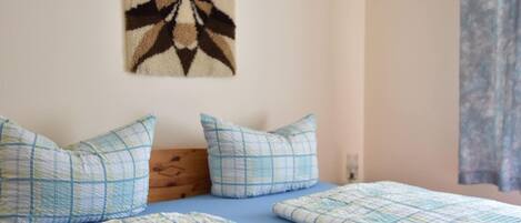 A bedroom with two beds, a wall hanging, and a wooden headboard.
