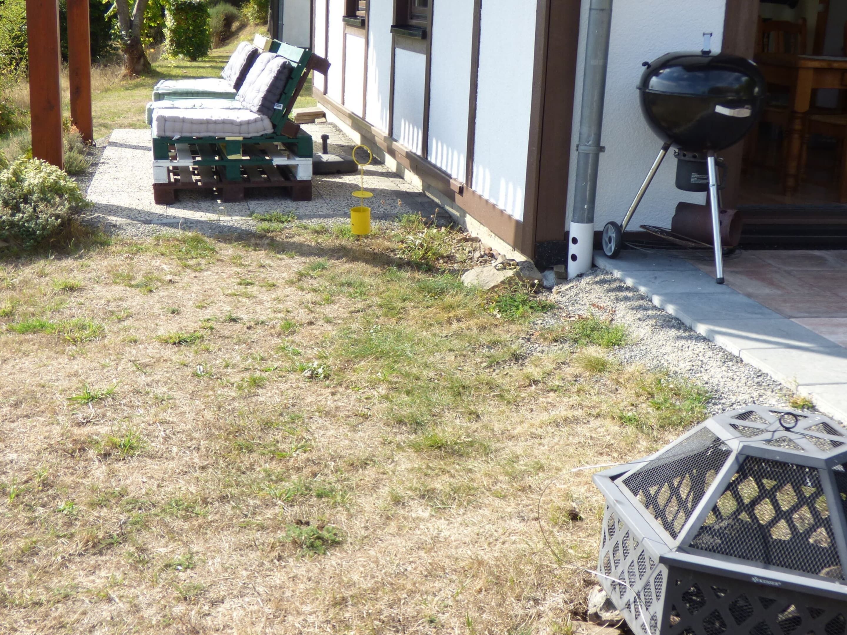 Une terrasse avec un barbecue, une petite table et une chaise.