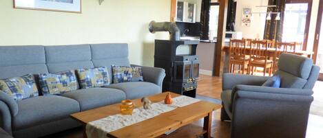A living room with a grey sofa, a wooden coffee table, and a kitchen area in the background.