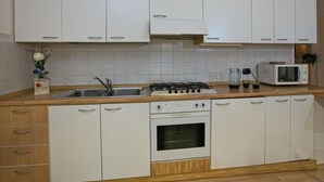 A kitchen with white cabinets, a stove, an oven, a microwave, and a sink. - Apartment in Predazzo Near Dolomiti Superski (Predazzo)