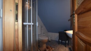 Un baño con ducha, inodoro, lavamanos y una pequeña alfombra en el suelo.