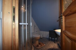 Ein Badezimmer mit Dusche, Toilette, Waschbecken und einer kleinen Fußmatte.
