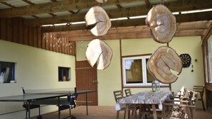 Un comedor con una mesa y sillas, una mesa de ping pong y leña colgando.