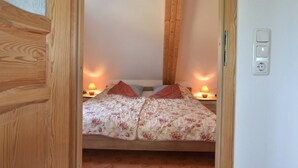 Un dormitorio con techo de madera, una cama con ropa de cama floral, dos lámparas de noche y una mesita de noche.