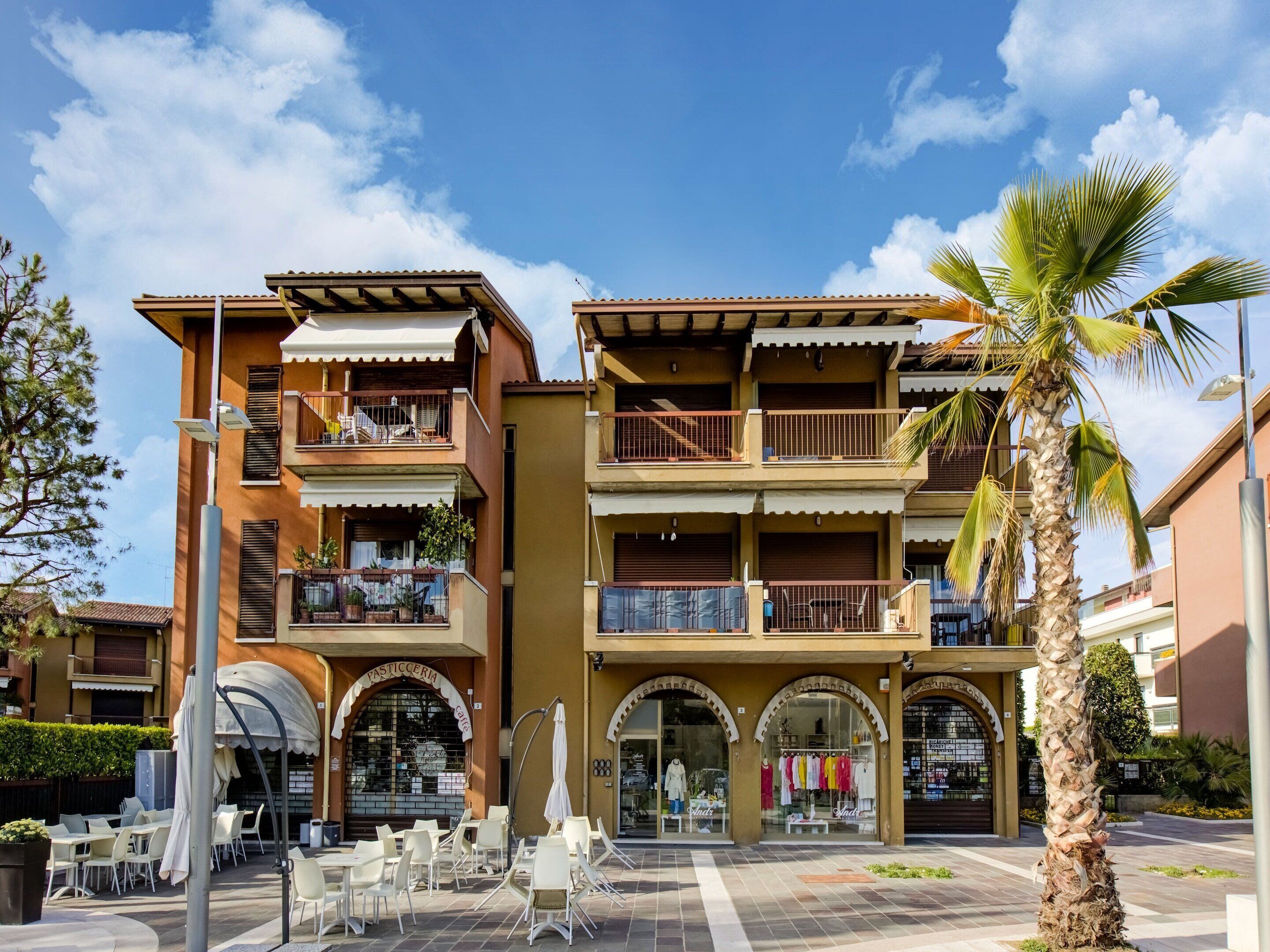 A multi-story building with balconies, outdoor seating, and a café.
