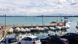 Ein Yachthafen mit vertäuten Booten, einer Mole und Blick auf Wasser und Himmel.