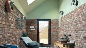 A sunroom with brick walls, two lounge chairs, a small table, and a large window. - Lovely Holiday House With Big, Private Garden, Near Well Known SPA Centre (Tuhelj)
