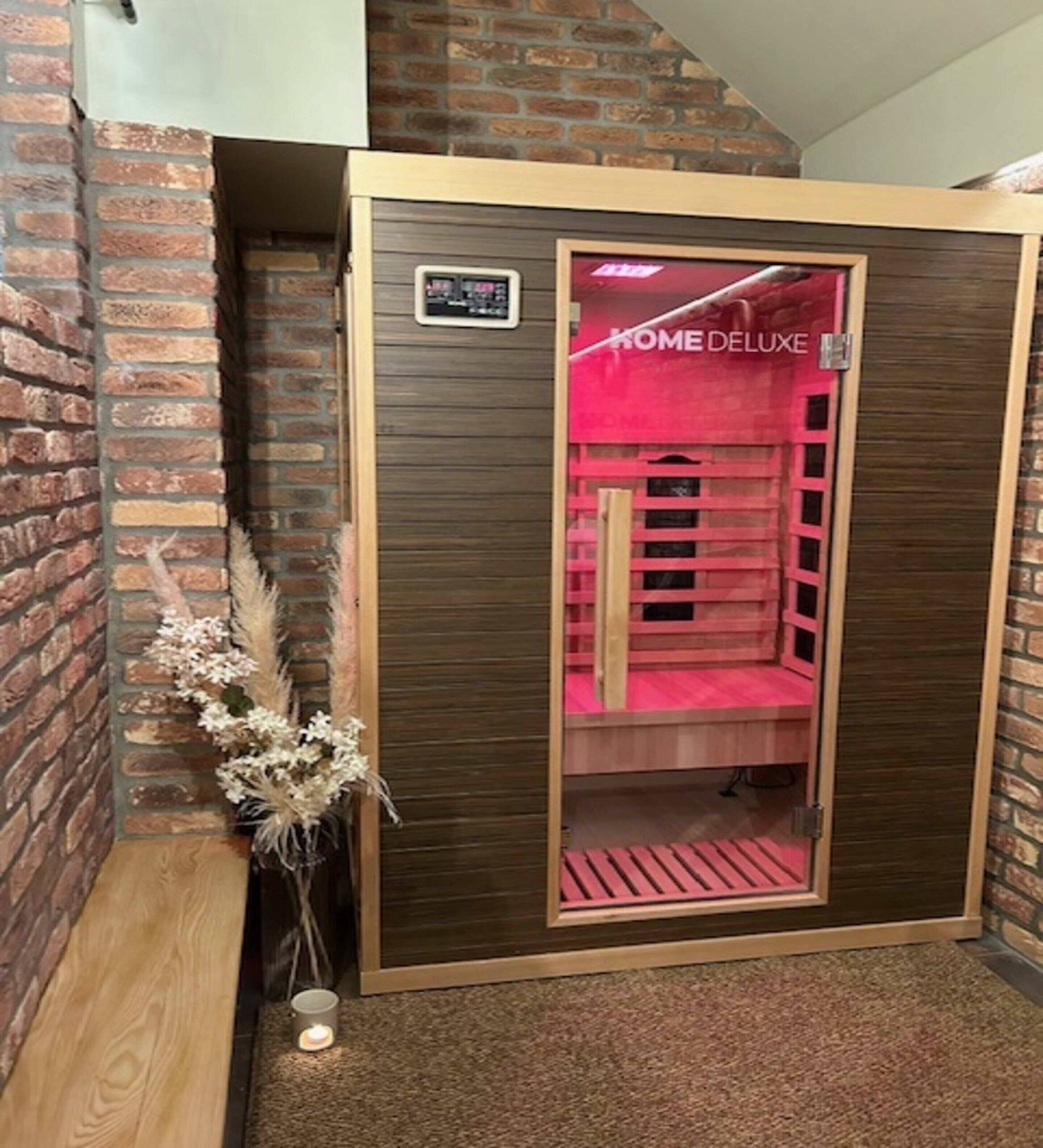 A room with a brick wall, a wooden cabinet with a glass door, and a small candle on the floor.