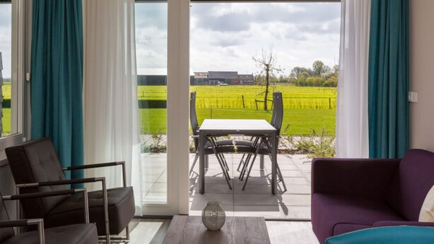 A modern living room with a view of a green field through large glass doors. - Serene Holiday Home in Oostkapelle near Center & Forest (Oostkapelle)