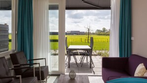 A modern living room with a view of a green field and a distant building. - Serene Holiday Home in Oostkapelle near Center & Forest (Oostkapelle)