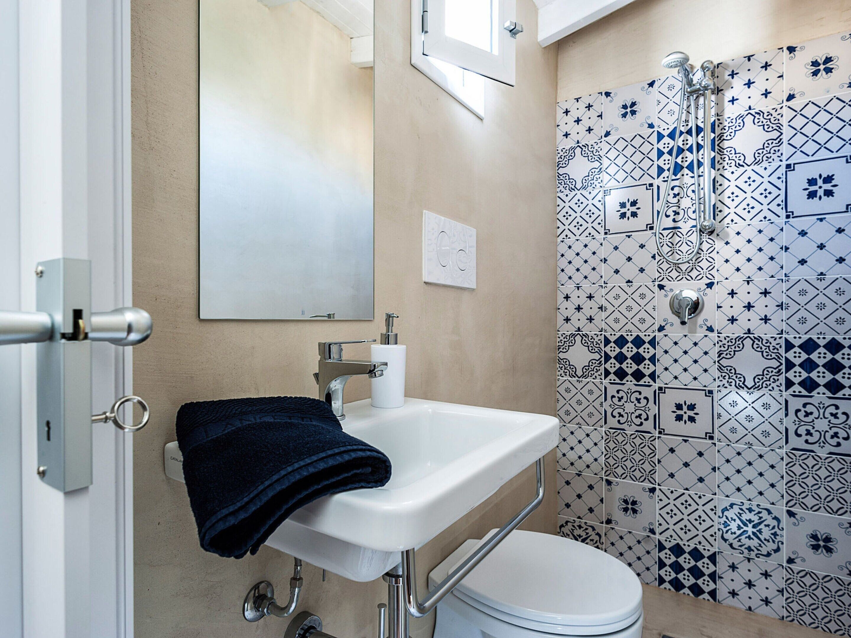 Een badkamer met een witte wastafel, toilet en douche met betegeling.