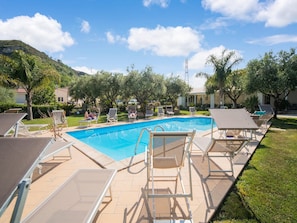 A swimming pool with lounge chairs and a grassy area.