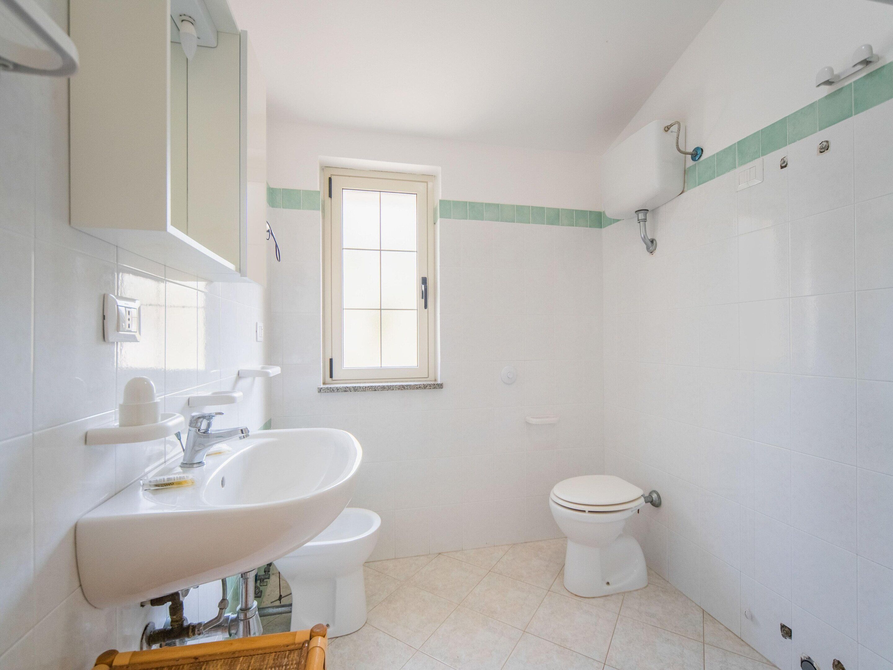 Un baño con lavamanos, inodoro y ventana.