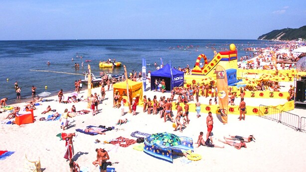 Une plage bondée, avec des structures gonflables et une tente.