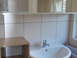A bathroom with a white sink, a wooden cabinet, and a mirror above the sink. - Delightful Apartment in Bastorf With Terrace (Bastorf)