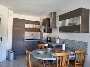 A compact kitchen with dark wood cabinets, a stainless steel range hood, and a tiled backsplash.