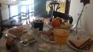 A dining table with breakfast items including bread, pastries, and orange juice. - Polyxenia Hotel (Nafplio)