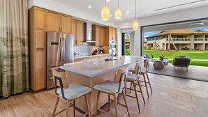 Una cocina moderna con armarios de madera, electrodomésticos de acero inoxidable y una isla grande con taburetes de bar.