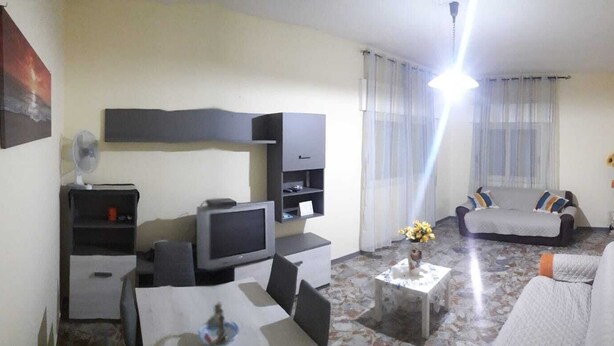 A living room with a TV, sofa, coffee table, and a fan. - Villa Artemide (Modica)