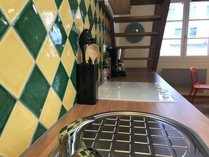 Une cuisine avec un dosseret de carreaux à motifs, un évier en acier inoxydable et une machine à café.