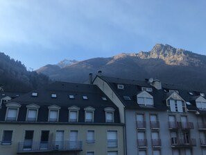 A row of residential buildings with sloped roofs and multiple windows, set against a backdrop of mountains. - Coeur de Cauterets, cosy T2 + mezzanine pr 4 Pers (Cauterets)