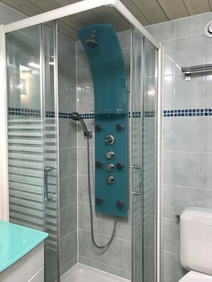A shower with a curved glass enclosure, a glass door, and a white toilet in a bathroom with tiled walls. - Coeur de Cauterets, cosy T2 + mezzanine pr 4 Pers (Cauterets)