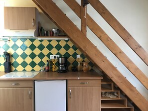 Une cuisine avec un escalier en bois, une machine à café et un réfrigérateur.