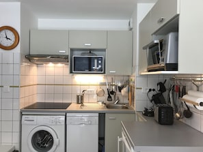 Una cocina compacta equipada con microondas, tostadora y lavadora.