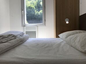 Makuuhuoneessa on kaksi sänkyä, ikkuna, josta on näkymä puita kohti, patteri ja seinään kiinnitetty valaisin.