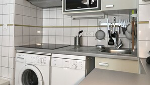 A modern kitchen with a Bosch washing machine, a microwave, and various utensils hanging on the wall. - T2 +alcove, récent 4/5 pers. Parking. Balcon. Wifi (Cauterets)