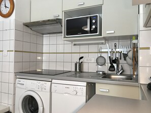 A modern kitchen with a Bosch washing machine, a microwave, and various utensils hanging on the wall.