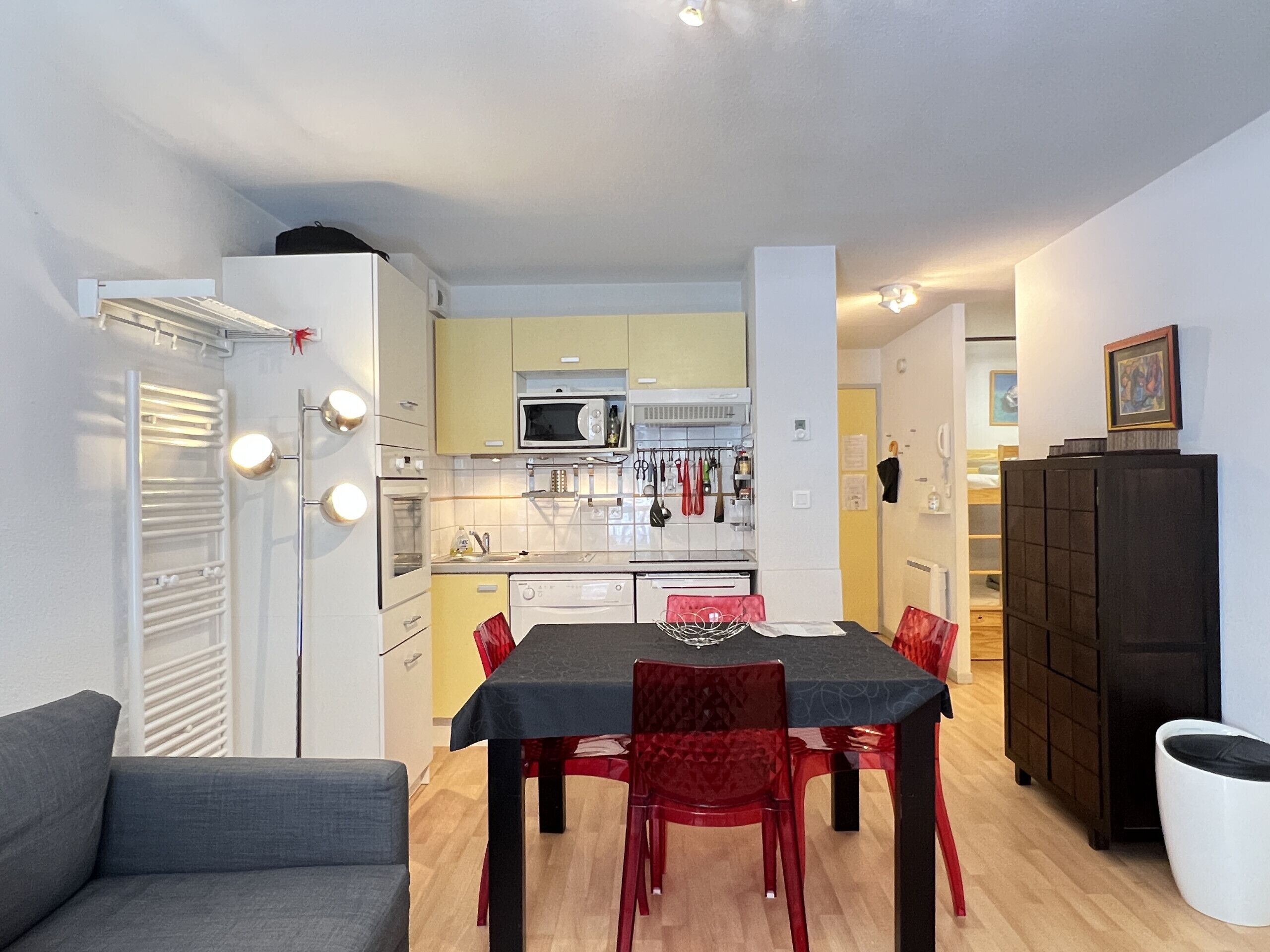 Une cuisine compacte équipée d’un four à micro-ondes, d’une cuisinière et d’un évier, ainsi qu’une table à manger avec des chaises et un canapé.