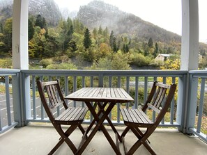 A wooden table and chairs on a balcony with a view of a forested mountain range.