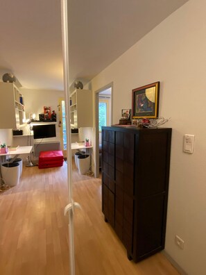 Una sala de estar moderna con un televisor de pantalla plana, un mueble negro y un reposapiés rojo.