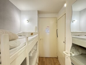 Pieni, kompakti huone, jossa on kerrossängyt, lukittava ovi ja peili yhdellä seinällä.