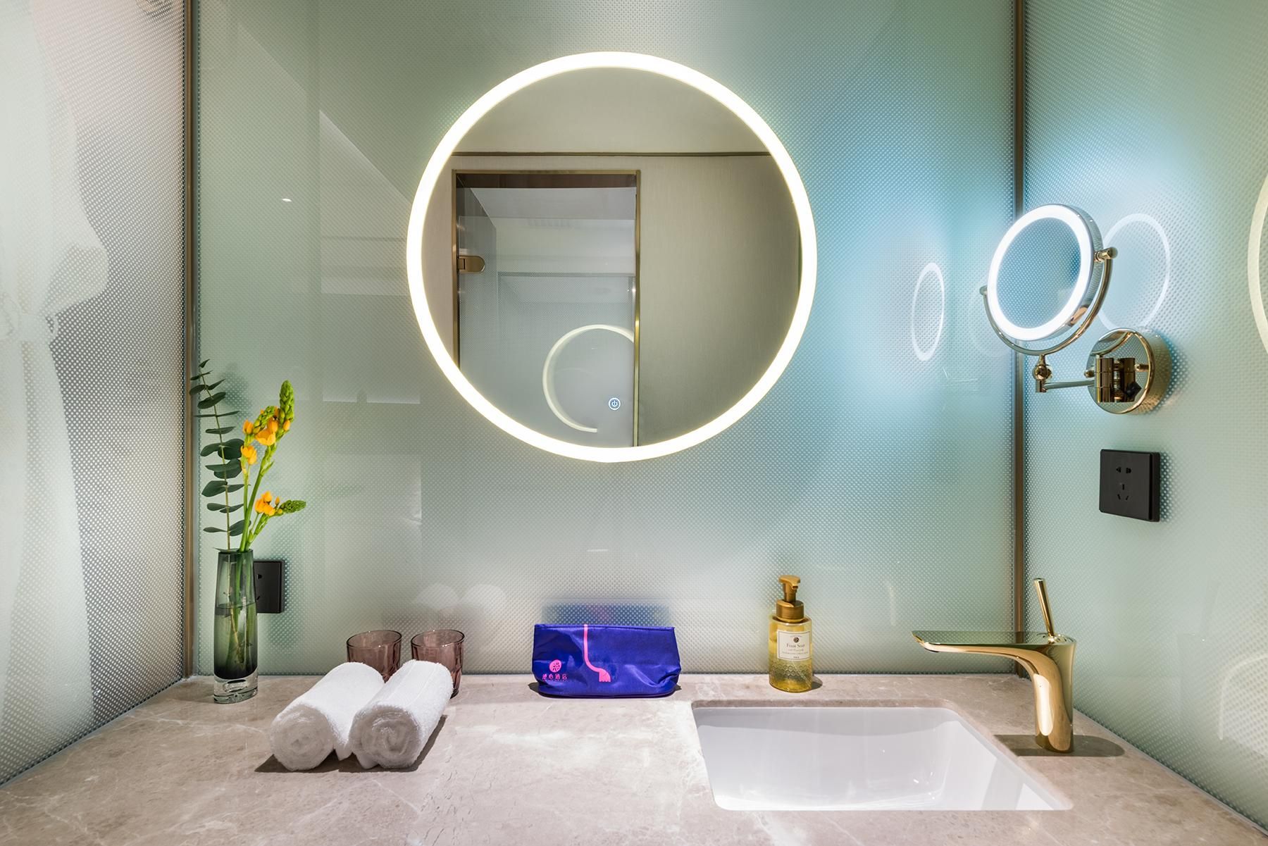 Un baño moderno con un espejo grande, un grifo dorado y un lavabo blanco.