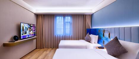 A hotel room with a television on a shelf, two beds, a headboard, and a window with curtains.